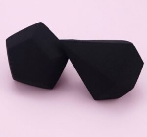 Des lunettes de soleil noires à monture géométrique reposent sur un fond rose pâle lisse et uniforme.